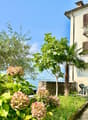 Two-story house with balcony, stone wall, garden, and lake view