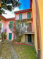 2 story house, brick facade, green windows, balcony, brick sidewalk