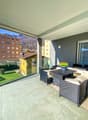 Balcony with glass railings, wooden furniture, potted plant, tiled floor, green lawn view