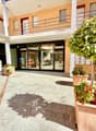 Apartment building entrance, balcony with railing, glass doors, greenery with flowering plants