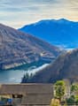 lake nestled between the mountains, residential houses with tiled roofs, dam on the lake, trees and shrubs
