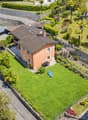 Large 2-story house, brown roof, garden, palm trees, large grass, lounge chair, solar panels on roof