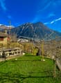 Stone house, stone bench, clothesline, green grass, mountain view