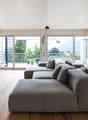 Wooden floor, large grey couch, TV, sliding glass doors to balcony