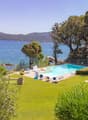 grassy lawn, swimming pool, chairs, pool side tables, view of the sea
