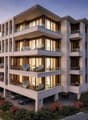 Modern multi-story building with multiple balconies, large windows, and a parking area.