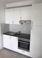 white cabinets, black countertop, stainless steel sink, stainless steel oven and stove, exhaust hood