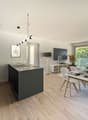 modern kitchen, dining table, couch, television, balcony with mountain view