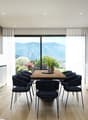 Modern kitchen with wooden table and chairs, glass door leading to balcony, wooden floors, white cabinets, sink, oven