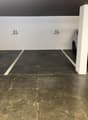 Underground parking lot with two parking spaces, white walls, grey floor, and white pillars