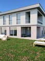 two-story house, glass windows, balcony on second floor, lawn, outdoor chairs, green lawn, large garden, trees