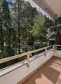 covered balcony, metal railings, tiled floor, surrounded by greenery