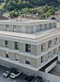 4 story building, concrete exterior, multiple windows, multiple balconies, underground parking, view of town and mountains