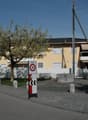 Yellow building with white fence, trees, benches, and a speed limit sign