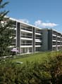 Modern apartment building with multiple floors, balconies, and a well-maintained garden area.