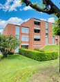 3 story brick building, multiple windows, hedges, trees, grass