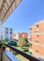 balcony, railing, plant pots, wind spinner, distant buildings, greenery, blue sky
