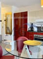 modern kitchen with red cabinets, black countertops, large dining table, modern chairs, glass, microwave, dishwasher, washing machine