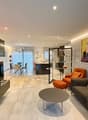 Modern and bright living room with a sofa, coffee table, flat screen TV, and paintings on the wall