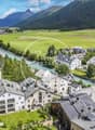 multi-story buildings, river, mountain landscape, surrounded by trees and greenery, flat roofs, gardens and driveways, yellow machinery in the river