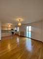 Empty room, open kitchen, wooden floor, white walls, two sliding doors, radiator, modern kitchen with black stove and kitchen island.