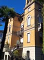 Two-story building, beige color, lots of balconies, plants