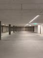 Empty parking lot with concrete floor, metal poles, and ceiling lights