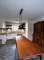 Spacious kitchen with a mix of modern and traditional elements. The kitchen features a large wooden dining table, a built-in fireplace, and a custom tile backsplash. The room also includes a wooden cabinet unit and stainless steel appliances.