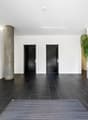 modern hallway, black tiled floor, white walls, two doors, potted plant, mailboxes