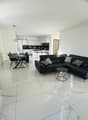 modern open plan living room, white marble flooring, sleek black leather sofa, modern dining table, white kitchen