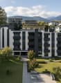 Modern apartment building with multiple floors, balconies, and a landscaped garden area.