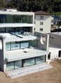 Modern building with glass walls, multiple balconies, roof terrace