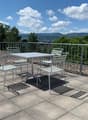 Outdoor table and chairs on a balcony with a view of the mountains