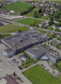 Large industrial/commercial complex with multiple buildings, parking lots, and surrounding residential and green areas.