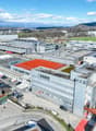 Industrial buildings with parking lots, solar panels on roofs, a red tennis court, multiple buildings, and surrounding area