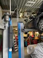 large metal rack system to lift cars, car in the middle, ladder against the wall, shelves with tools and equipment, car underneath a cover