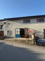 2 story house, concrete exterior, large windows, several cars parked in front, garage entrance, wooden posts, some clutter in the front