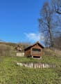 Small house built on slope, wooden structure, metal roof, glass window, wooden fence