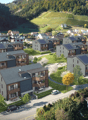 Aerial view of a residential area with multi-story apartment buildings, surrounded by lush greenery and vineyards on the hills in the background.