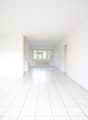 Empty room with white walls and floor, two doors, window with white radiator