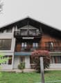 2 story house, wooden trim, white walls, balcony, shrubs, garden, and a tree in front