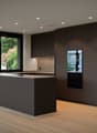 modern open-plan kitchen, grey cabinets, island with built-in stove, large windows, large kitchen appliances