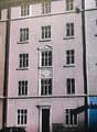 3 story building, pink walls, multiple windows, centered door