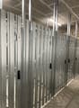 The image shows a row of gray metal storage lockers or compartments, likely in a storage facility or warehouse. The lockers have numbered doors and appear to be arranged in a long row with a high ceiling overhead.