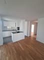 modern kitchen with white cabinets, black countertops, wooden floors, built-in oven and sink