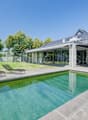 Modern house with solar panels, large windows, swimming pool, loungers, garden, trees