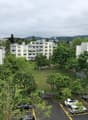Aerial view of a residential building complex with multiple buildings, parking area, and a grassy field.