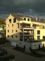Yellow apartment building with solar panels, multiple balconies, garages and cars parked in front