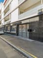 Modern apartment building, white exterior, glass doors, balconies, multiple windows, street view