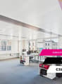 Open floor plan, desks, chairs, monitors, bookshelves, cabinets, radiators, carpeted floor, windows
